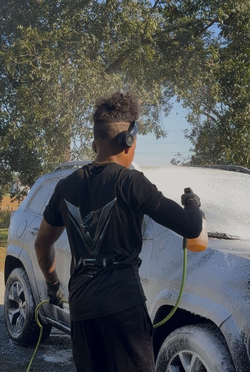 Clark Davenport hand-washing a vehicle in a VEIL shirt